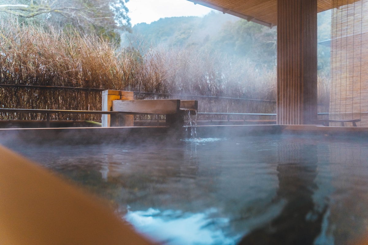 Steam rising from an outdoor thermal bath with wooden architecture - Korean jjimjilbang spa experience