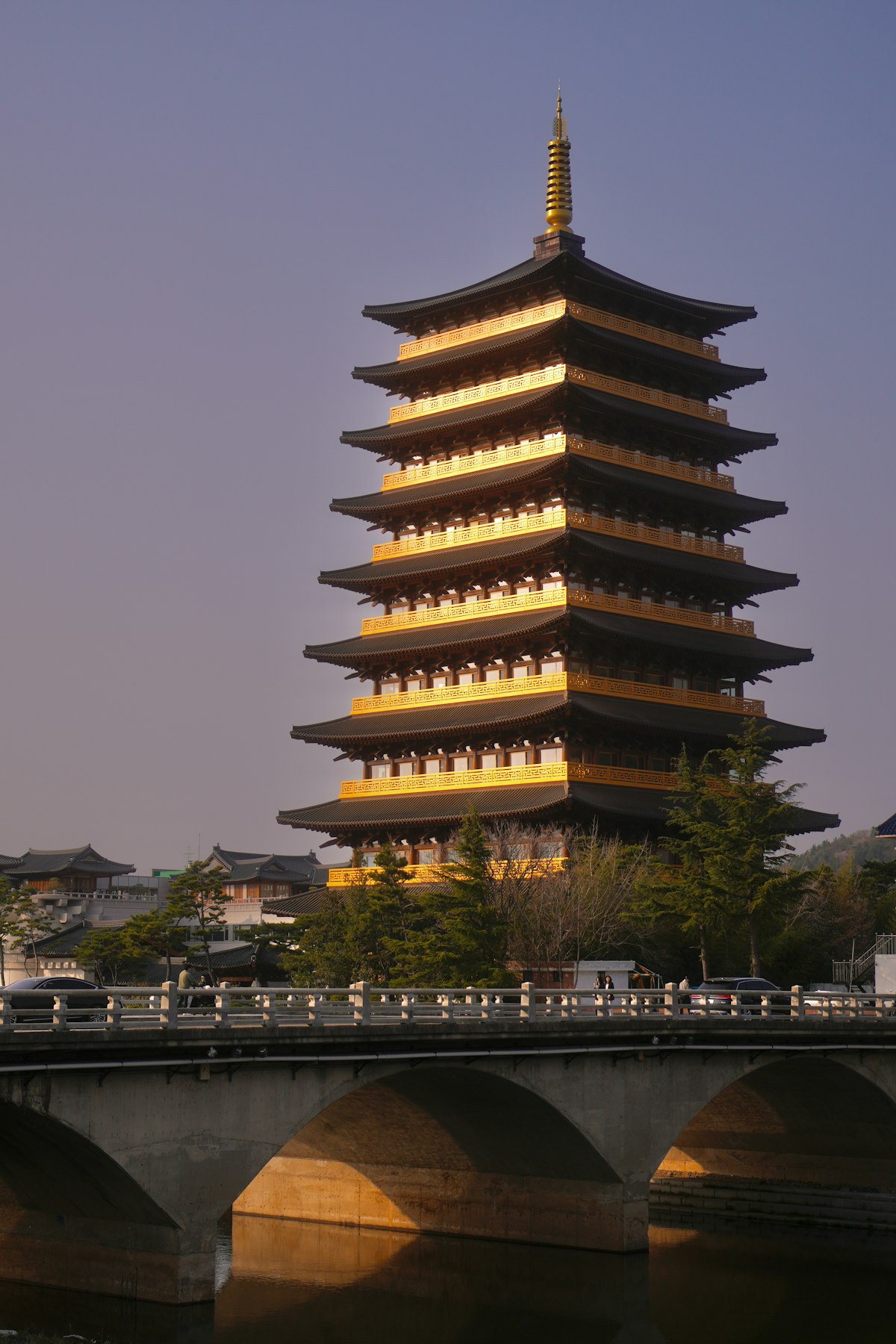 Golden illuminated multi-storey pagoda in Gyeongju with arched stone bridge at dusk