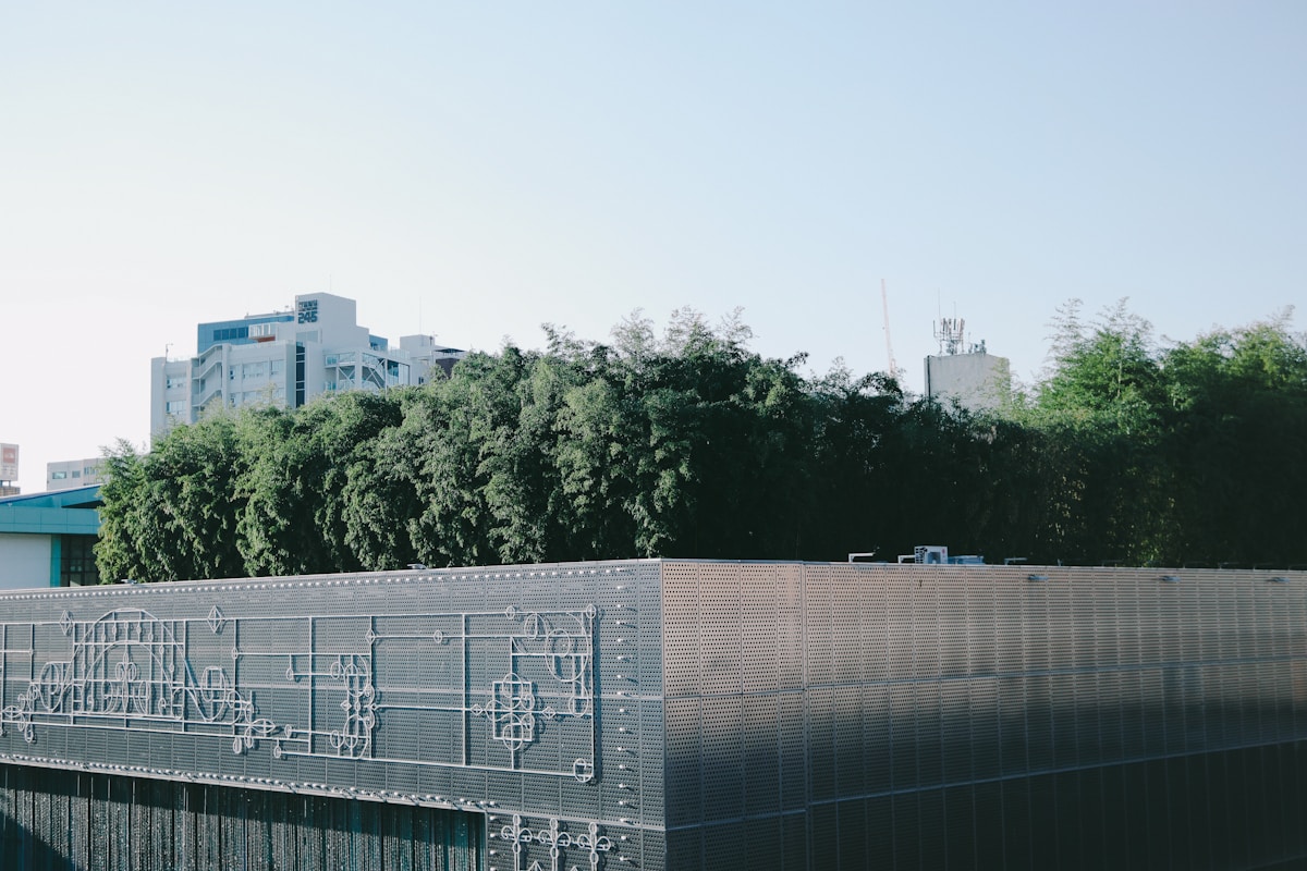 Modern metallic building facade with perforated decorative panels and green trees in Gwangju, South Korea