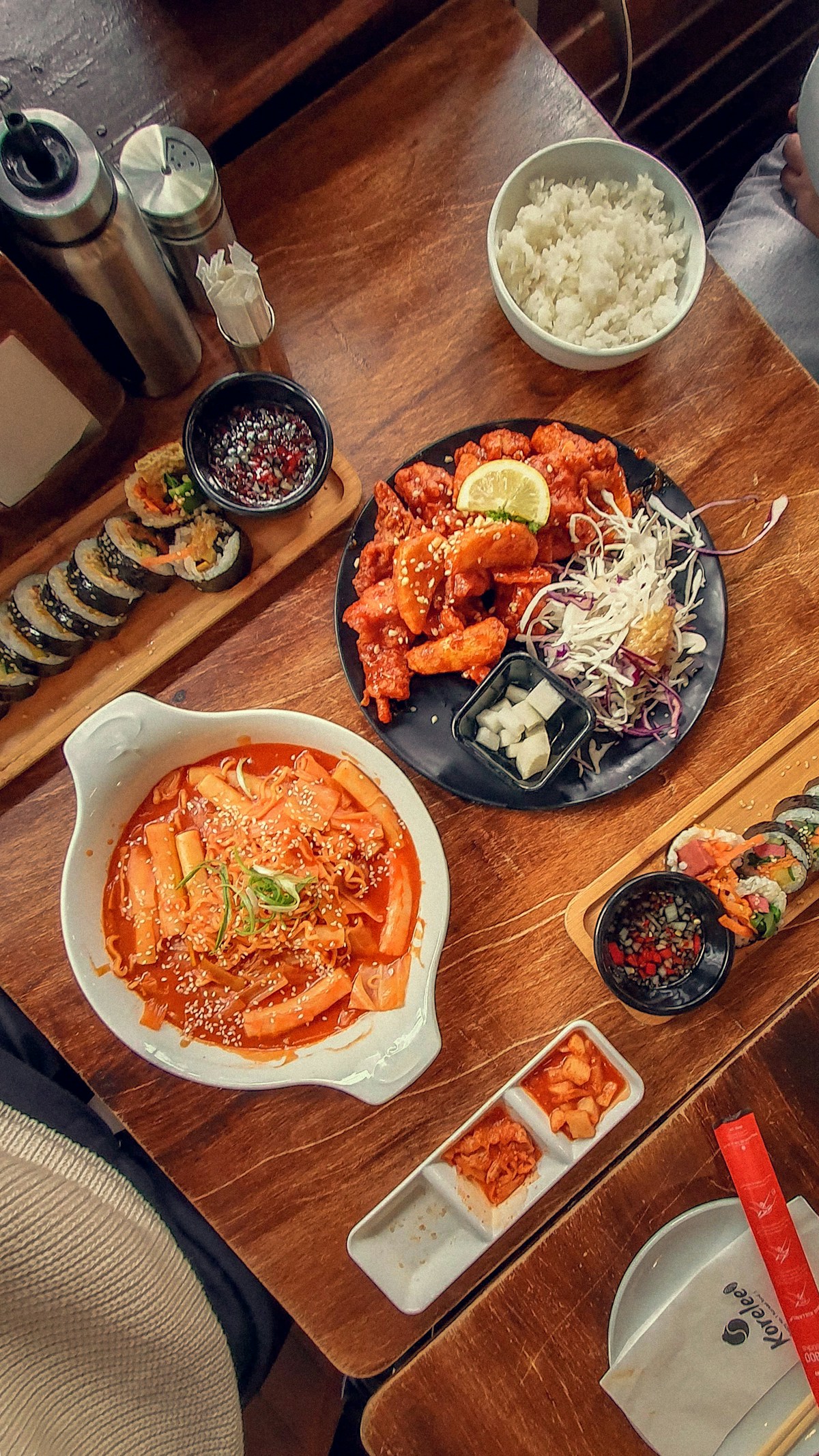 Korean cuisine spread with tteokbokki, gimbap and fried chicken on a wooden table