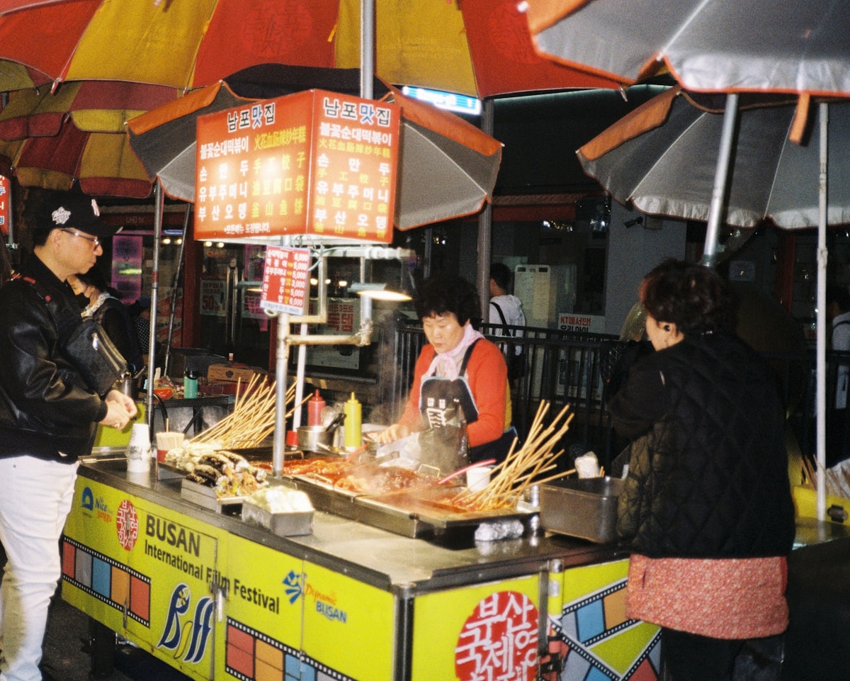 Tteokbokki rice cakes simmering in red gochujang sauce at a market food stall in Seoul