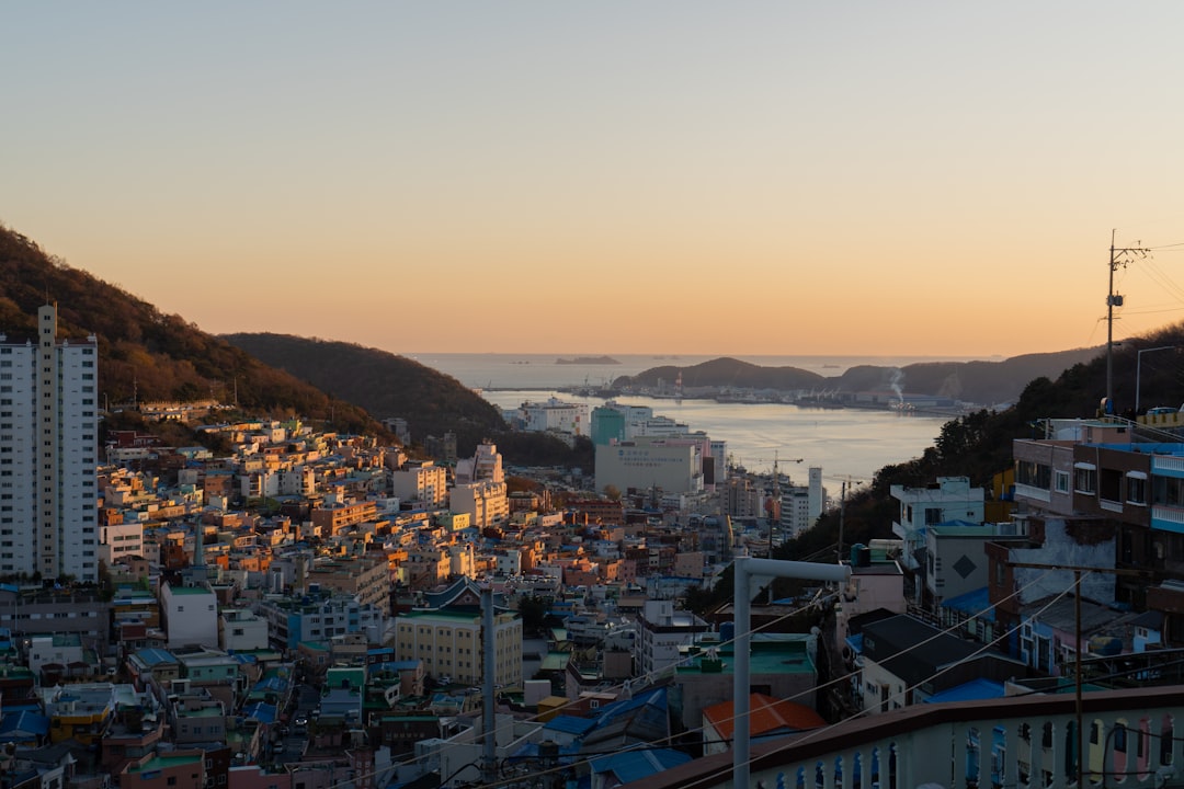 Busan's colorful hillside neighbourhood at sunset with the bay and mountains in the background