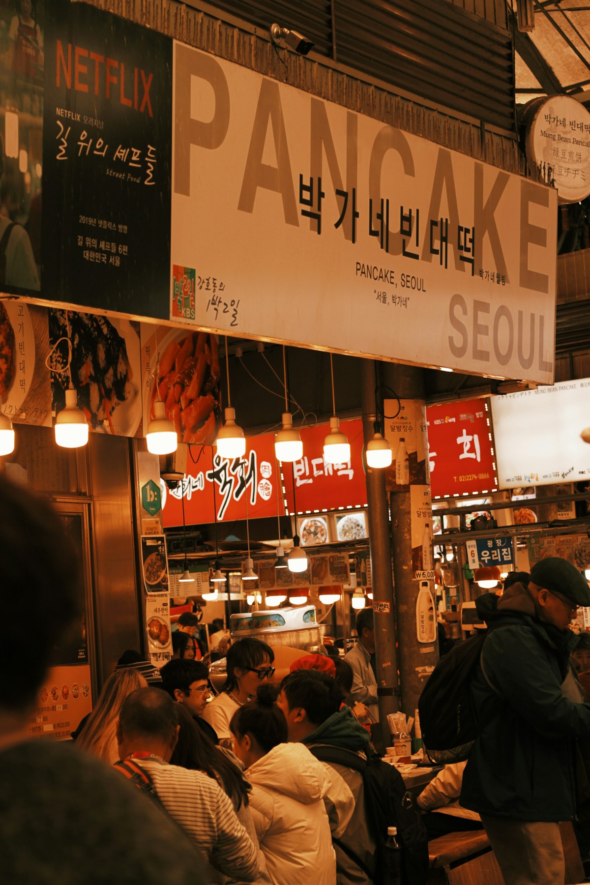 Bustling indoor food market stall in Seoul with Korean signs and diners - South Korea travel budget guide