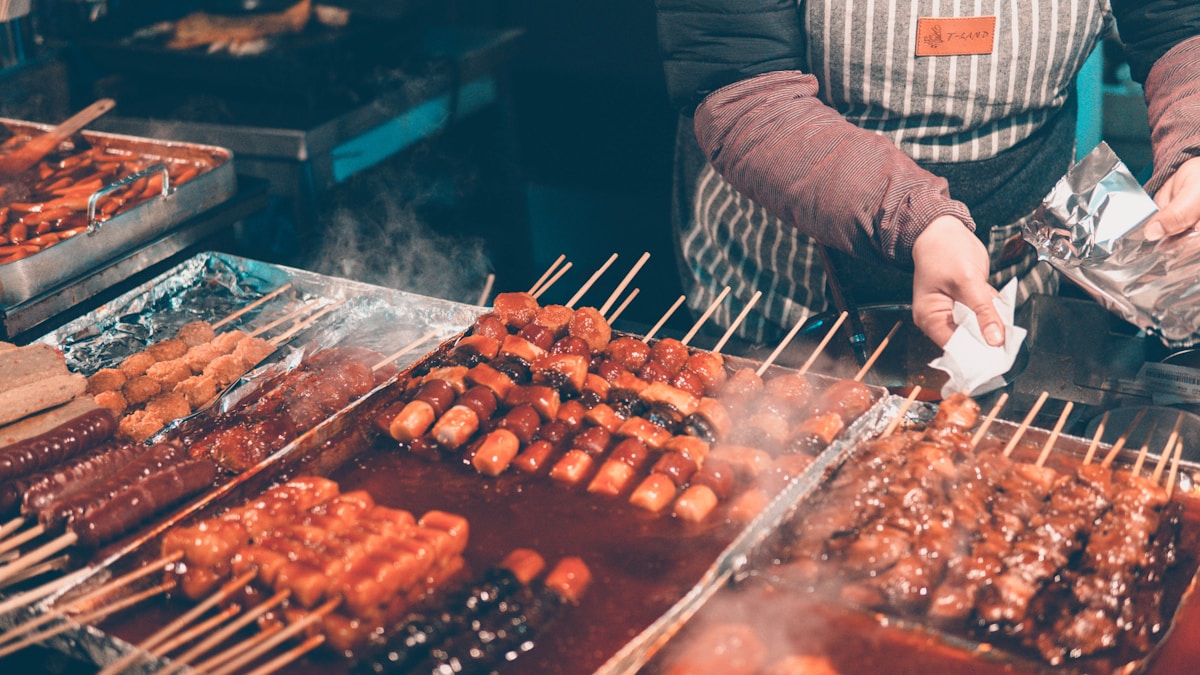 Street food vendor tending skewered Korean snacks on a grill in Myeong-dong, Seoul