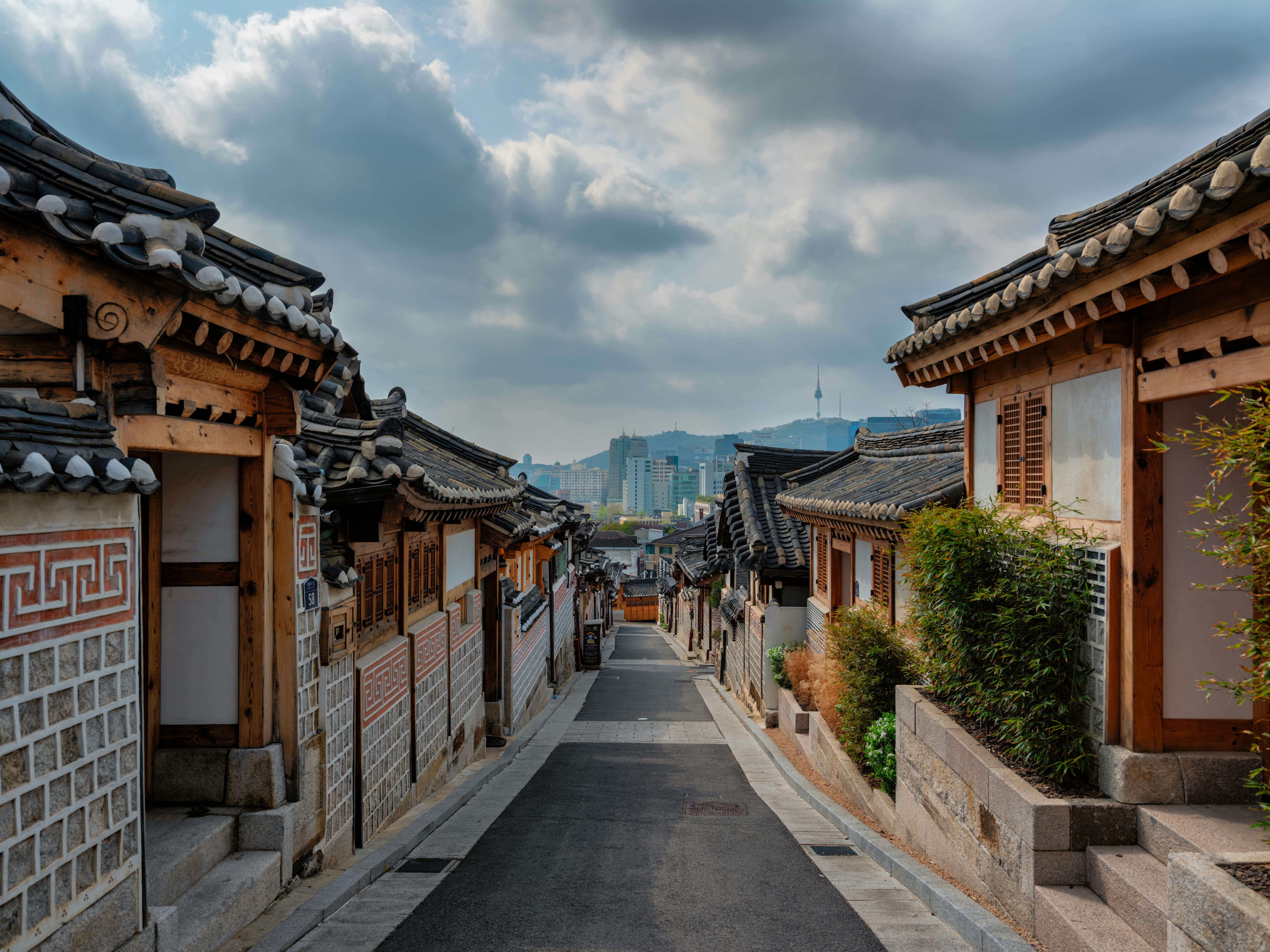 Traditional hanok alleyway with curved tiled roofs and Seoul Tower in the background, Seoul