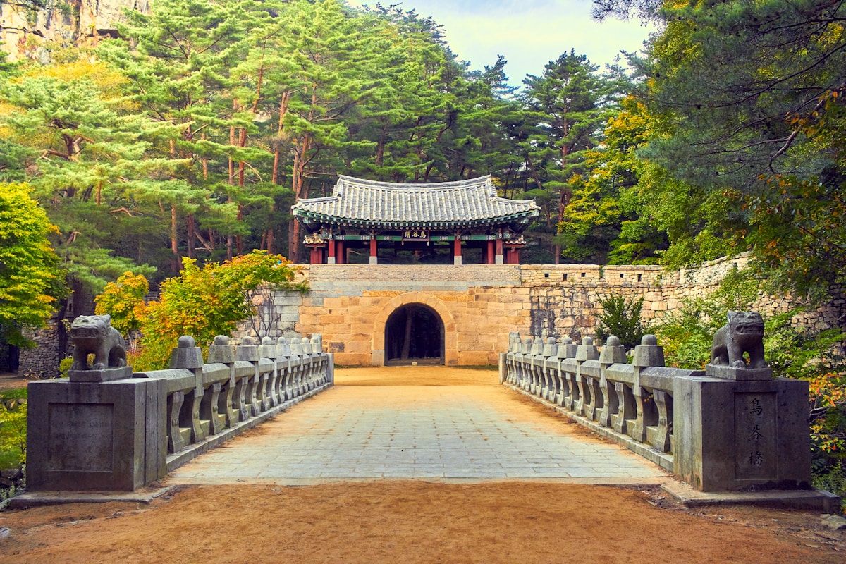 Stone archway gate of Hwaseong Fortress with traditional Korean tile rooftop against blue sky in Suwon, South Korea