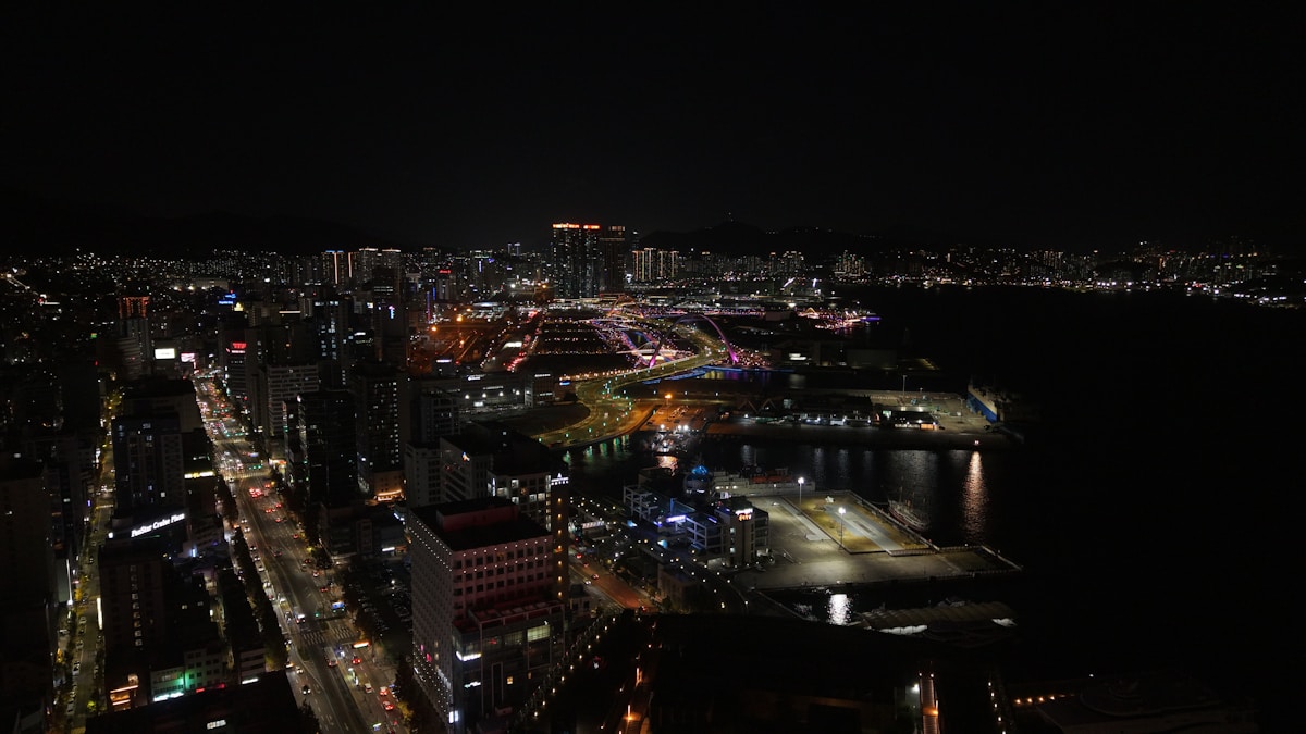 Night aerial view of a Korean coastal city with harbour lights reflected in the water